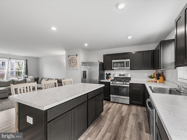 kitchen with a center island, sink, light hardwood / wood-style flooring, stainless steel appliances, and a kitchen breakfast bar