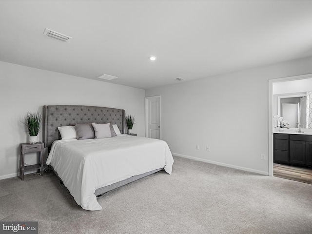 bedroom with ensuite bath, sink, and light colored carpet