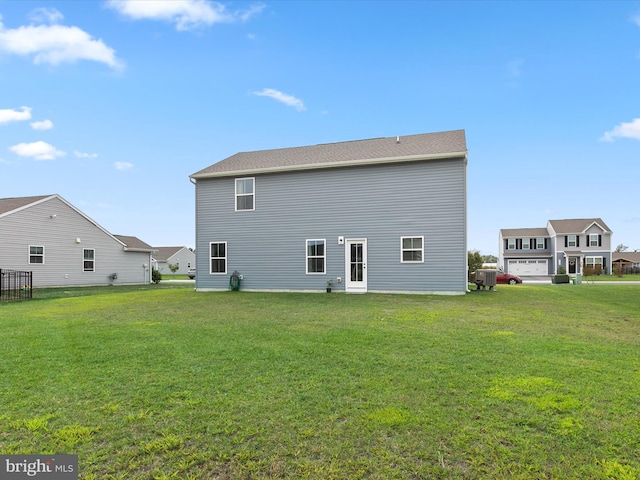 rear view of house featuring a yard and a garage