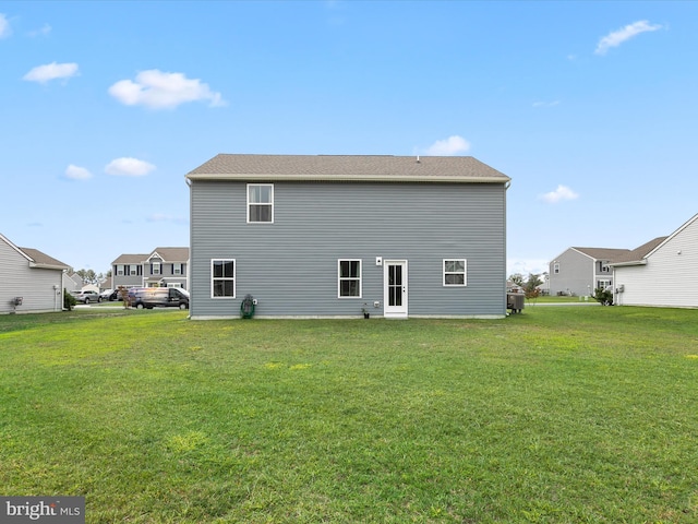 rear view of property featuring a lawn and cooling unit