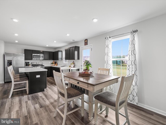 kitchen featuring sink, a kitchen island, light hardwood / wood-style flooring, stainless steel appliances, and a breakfast bar