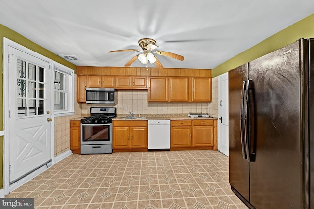 kitchen with decorative backsplash, stainless steel appliances, ceiling fan, and sink