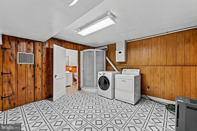 clothes washing area with washer and dryer and wooden walls