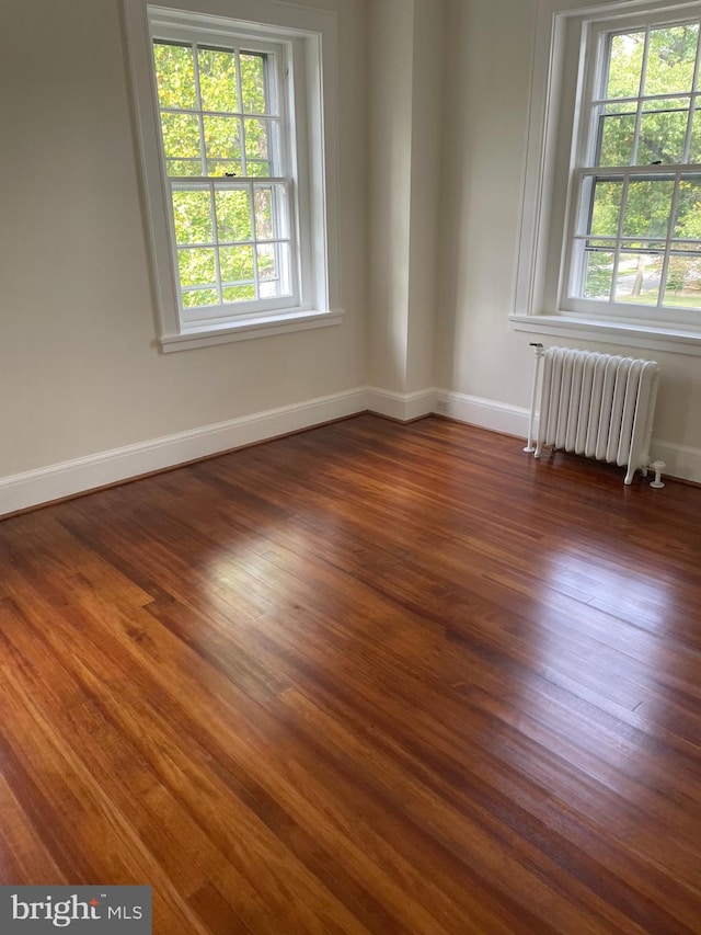 spare room featuring dark hardwood / wood-style floors and radiator heating unit