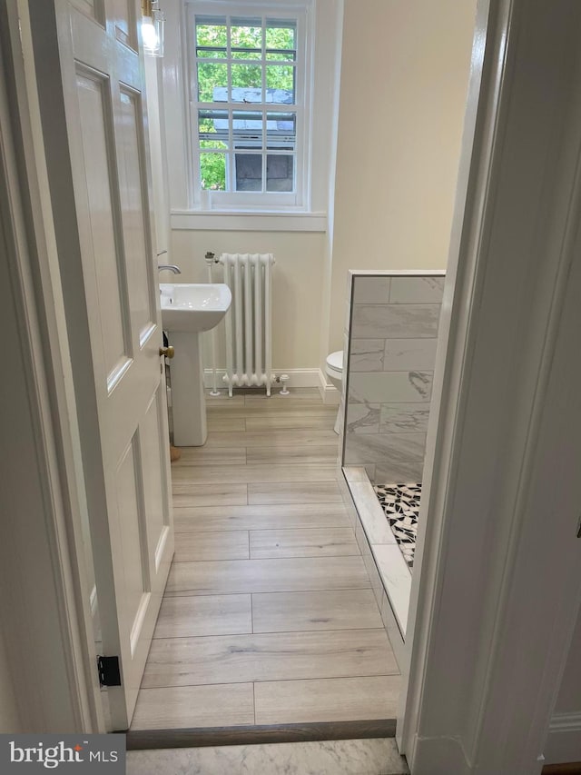 bathroom with radiator, a shower, toilet, and hardwood / wood-style flooring