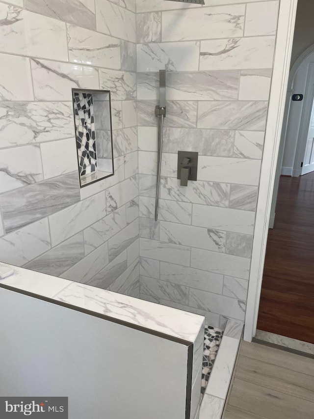 details featuring a tile shower and hardwood / wood-style flooring