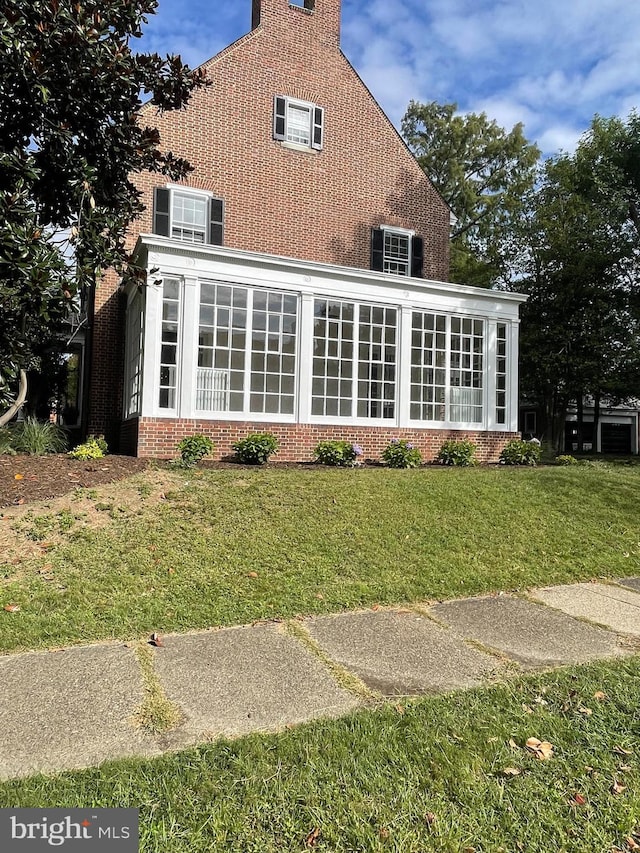 rear view of house with a lawn and a sunroom