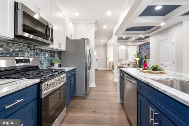 kitchen with blue cabinets, white cabinets, stainless steel appliances, and light hardwood / wood-style floors