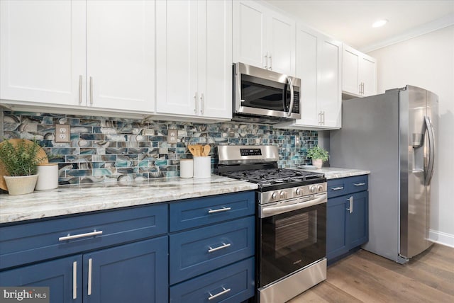 kitchen with white cabinets, ornamental molding, tasteful backsplash, stainless steel appliances, and light hardwood / wood-style floors