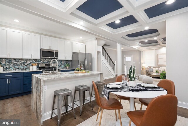 kitchen with white cabinetry, appliances with stainless steel finishes, dark hardwood / wood-style floors, and a kitchen island with sink