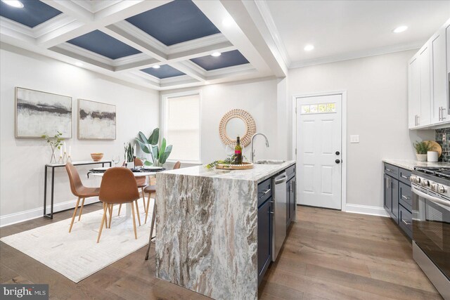 kitchen with appliances with stainless steel finishes, white cabinets, a center island with sink, hardwood / wood-style floors, and sink