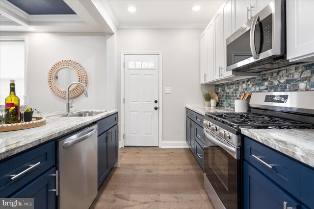 kitchen featuring appliances with stainless steel finishes, crown molding, light stone counters, and white cabinets