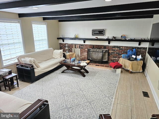 living room featuring beamed ceiling and a brick fireplace