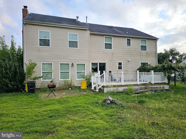 rear view of property featuring a deck and a lawn