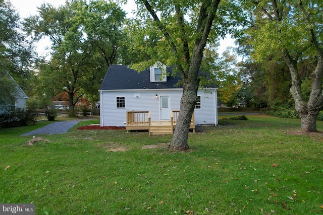 rear view of property featuring a lawn and a wooden deck