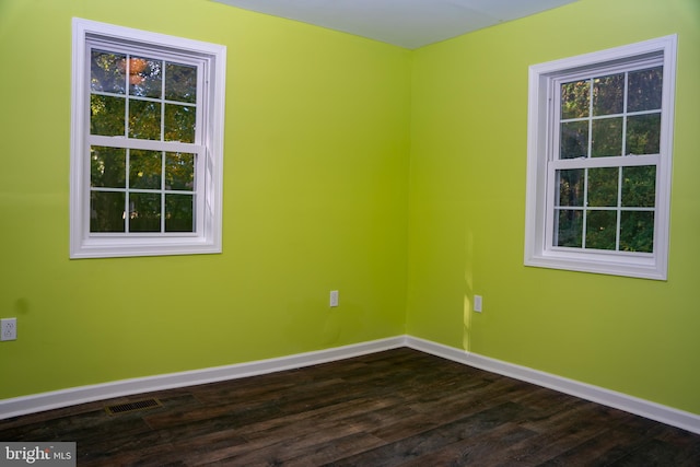 unfurnished room with visible vents, baseboards, and dark wood finished floors