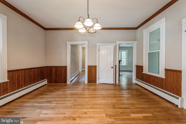 unfurnished room with baseboard heating, ornamental molding, light wood-type flooring, and a chandelier