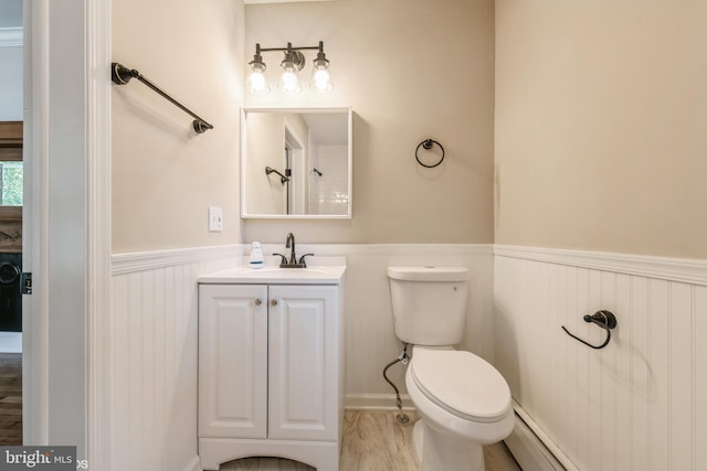 bathroom featuring vanity, toilet, hardwood / wood-style flooring, and a baseboard radiator