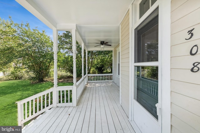 deck with ceiling fan, a lawn, and a porch