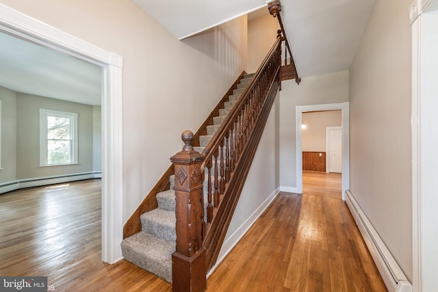 stairway featuring baseboard heating and hardwood / wood-style floors