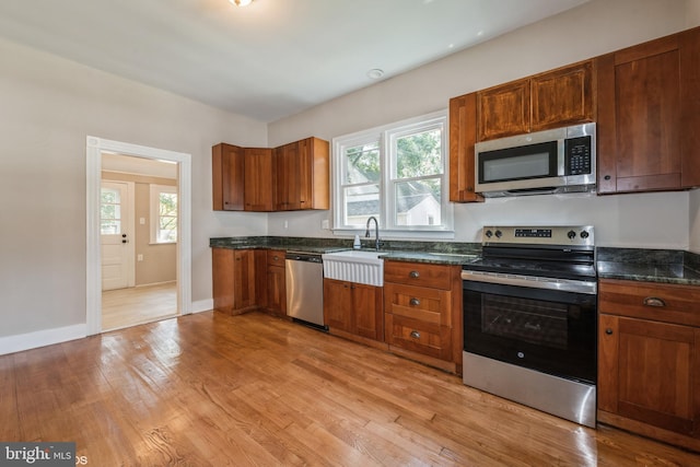 kitchen with light hardwood / wood-style flooring, dark stone countertops, sink, and appliances with stainless steel finishes