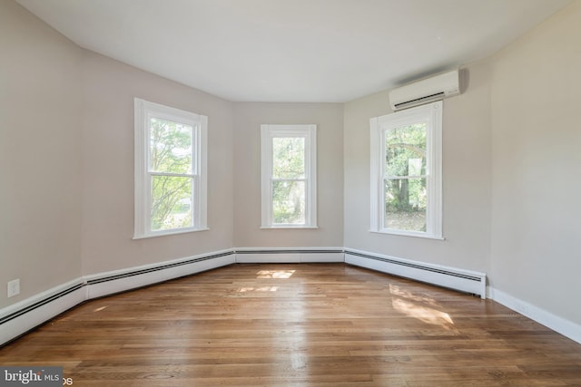 empty room featuring a healthy amount of sunlight, a baseboard radiator, an AC wall unit, and wood-type flooring