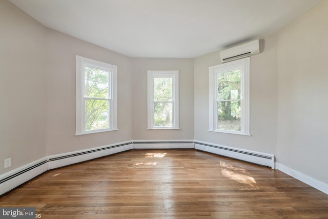 spare room featuring wood finished floors, a wall mounted AC, baseboards, and a baseboard radiator