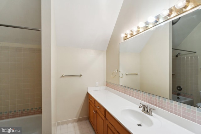 bathroom featuring vanity, tiled shower / bath, and lofted ceiling