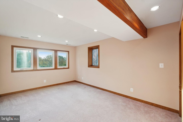 carpeted empty room with beam ceiling