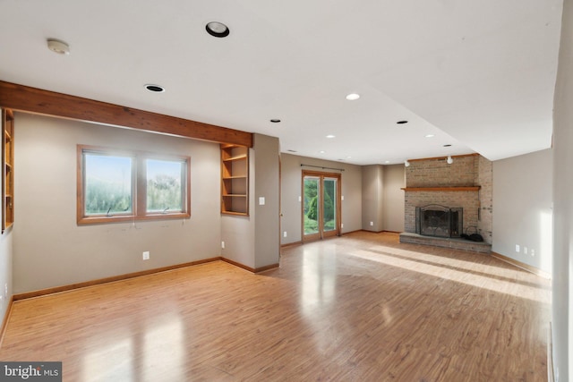 unfurnished living room featuring light hardwood / wood-style floors, a healthy amount of sunlight, and a brick fireplace