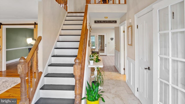 stairs with crown molding, hardwood / wood-style flooring, and a barn door