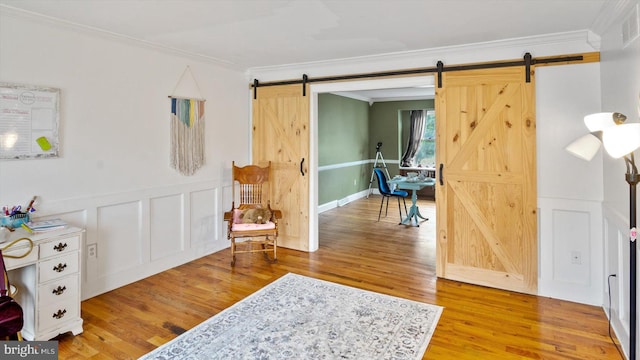 living area with crown molding, hardwood / wood-style floors, and a barn door