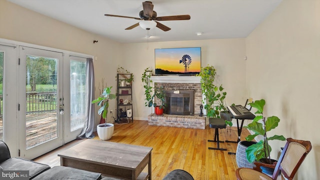 living room with ceiling fan, light hardwood / wood-style flooring, and a brick fireplace