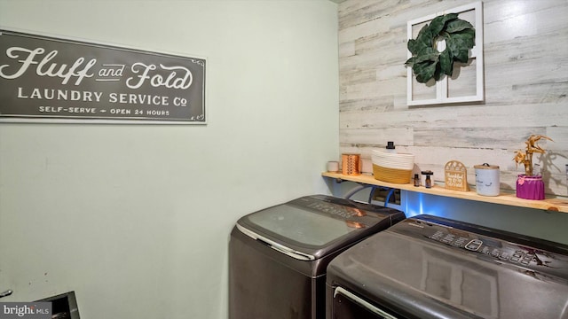 laundry room featuring wooden walls and independent washer and dryer