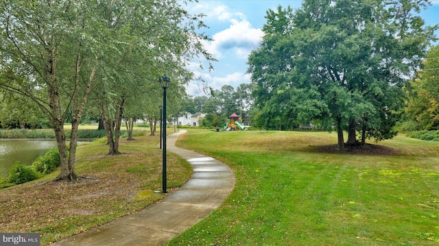 view of home's community with a lawn, a playground, and a water view