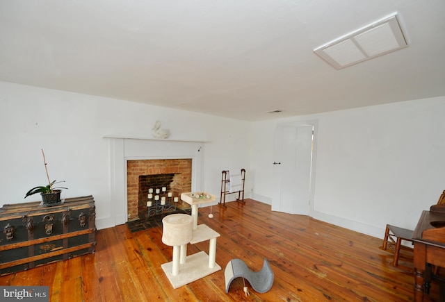 living area featuring a brick fireplace and wood-type flooring