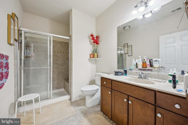 bathroom featuring tile patterned flooring, vanity, toilet, and a shower with shower door