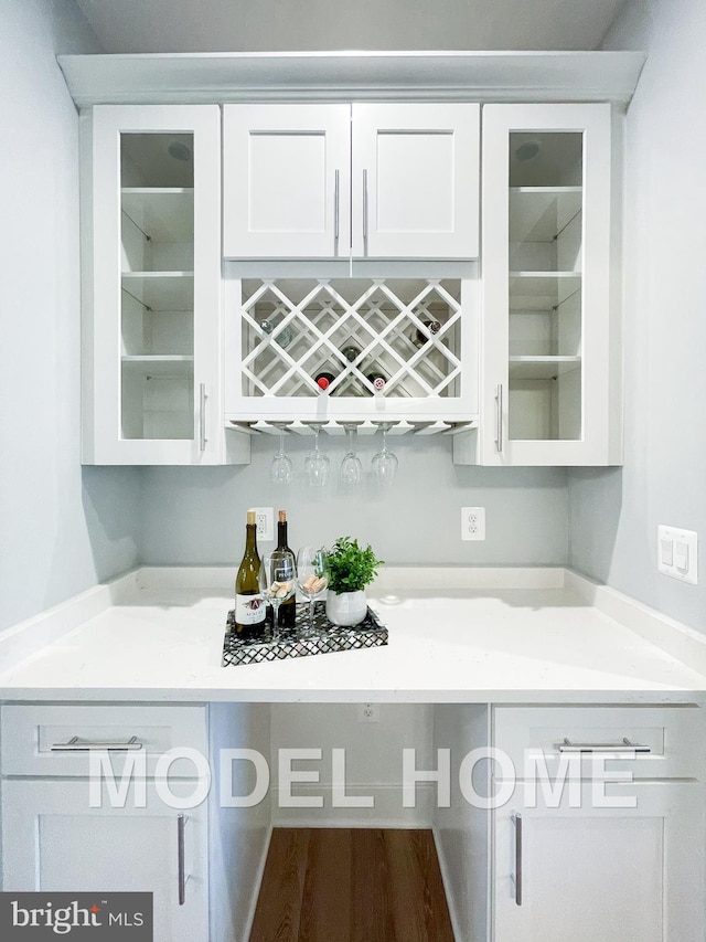 bar with white cabinets and hardwood / wood-style floors