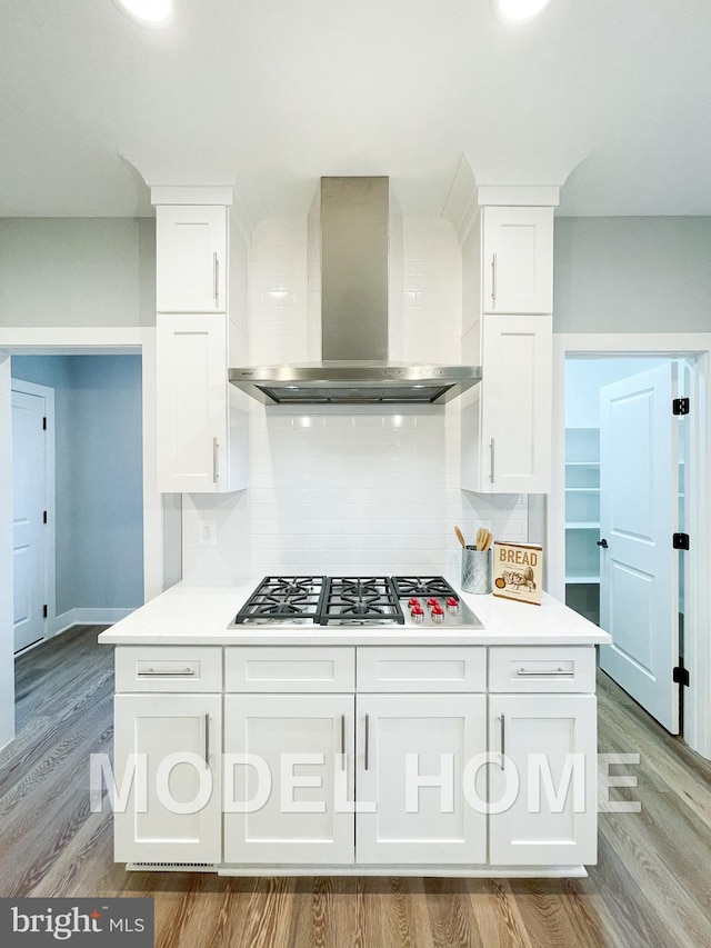 kitchen with white cabinets, wall chimney range hood, and backsplash