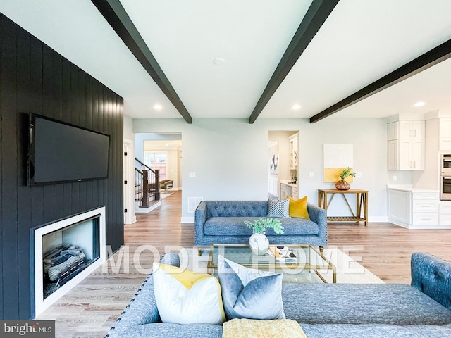 living room featuring a fireplace, beam ceiling, and light hardwood / wood-style floors