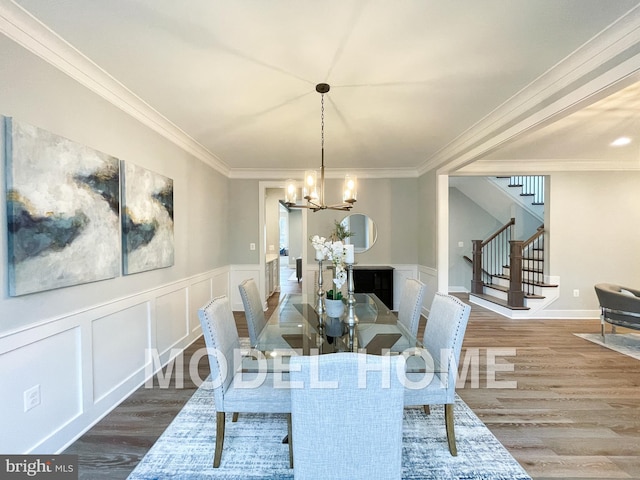 dining space with hardwood / wood-style flooring, a notable chandelier, and ornamental molding