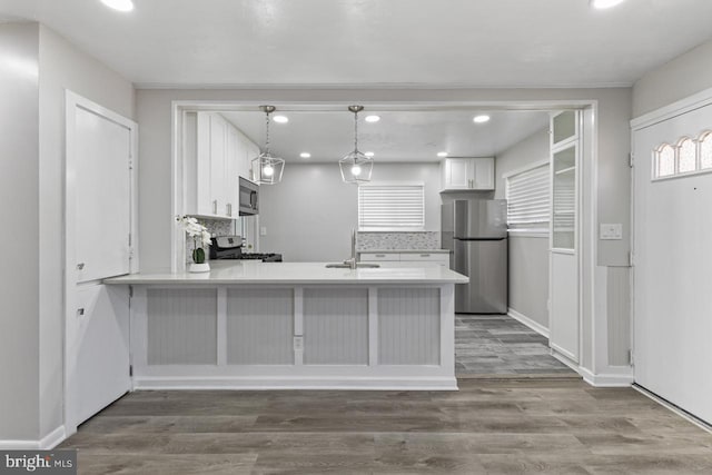 kitchen featuring pendant lighting, white cabinetry, kitchen peninsula, and stainless steel appliances