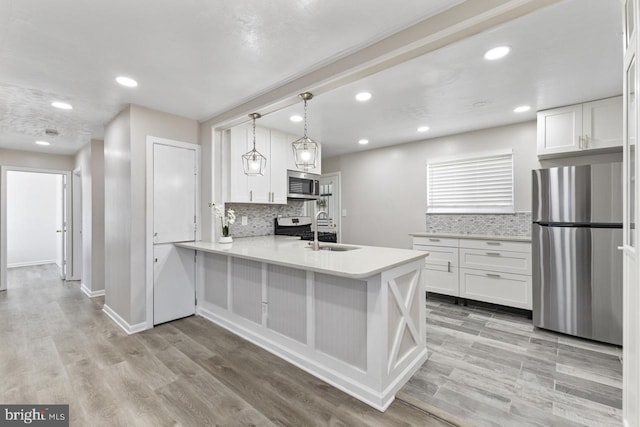 kitchen with appliances with stainless steel finishes, white cabinetry, kitchen peninsula, and sink