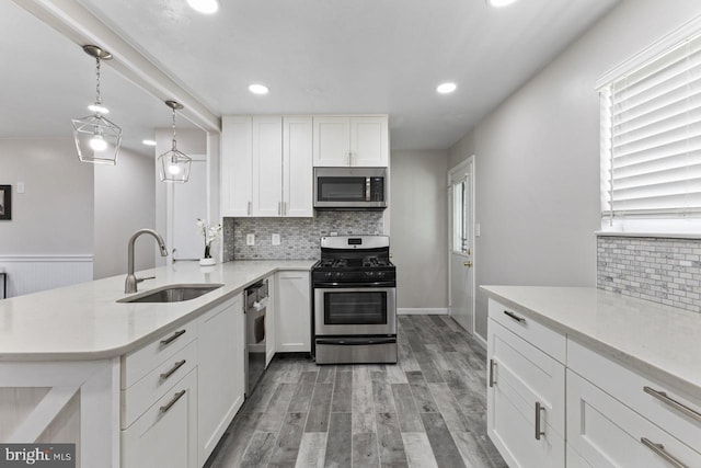 kitchen with hanging light fixtures, light hardwood / wood-style flooring, appliances with stainless steel finishes, white cabinetry, and sink