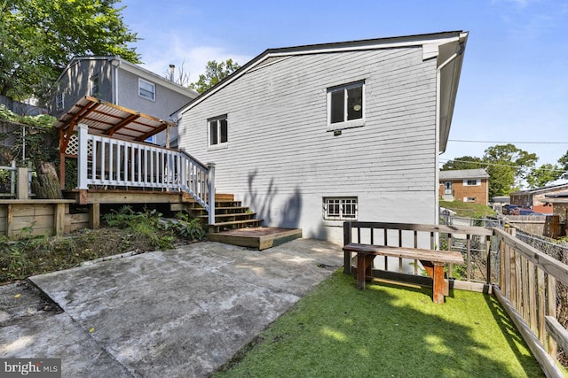 rear view of house with a lawn, a patio area, and a deck