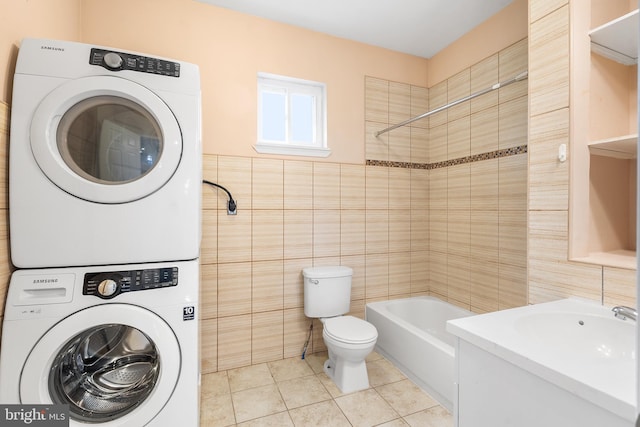 laundry area featuring stacked washing maching and dryer, tile walls, and light tile patterned floors