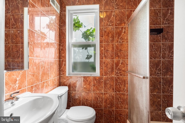 bathroom featuring tile walls, toilet, and sink