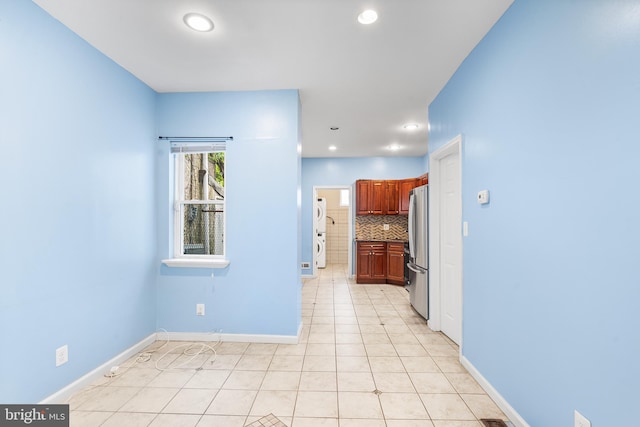 interior space featuring backsplash, stainless steel refrigerator, and light tile patterned flooring