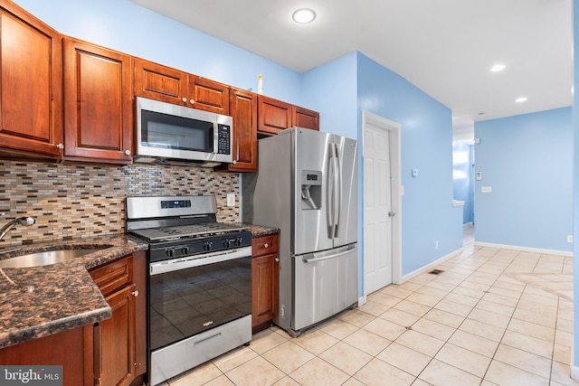 kitchen with light tile patterned floors, appliances with stainless steel finishes, sink, decorative backsplash, and dark stone counters