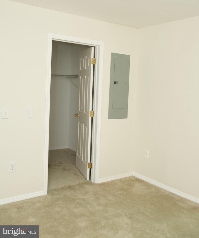 unfurnished bedroom with a closet, light colored carpet, and electric panel